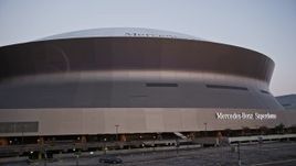 5K aerial stock footage of a slow descent and landing by the Superdome at sunset, Downtown New Orleans, Louisiana Aerial Stock Footage | AX61_079