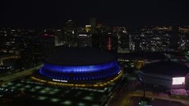 5K aerial stock footage of reverse view of the Superdome, New Orleans Arena, and skyscrapers at night, Downtown New Orleans, Louisiana Aerial Stock Footage | AX62_002