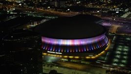 5K aerial stock footage of orbiting the Superdome as the lights change colors at night, Downtown New Orleans, Louisiana Aerial Stock Footage | AX63_024