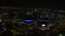 5K aerial stock footage orbit Superdome and New Orleans Arena to reveal Downtown New Orleans skyscrapers at night, Louisiana Aerial Stock Footage | AX63_026