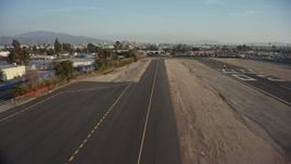 5K aerial stock footage of lifting off from the runway at Whiteman Airport, fly over homes and warehouse buildings, Pacoima, California Aerial Stock Footage | AX64_0047E