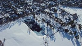 4.8K aerial stock footage of a frozen pond and suburbs in snow, Old Westbury, New York Aerial Stock Footage | AX66_0022E