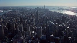 4.8K aerial stock footage fly over Midtown's skyscrapers, approach the famous Empire State Building in snow, New York City Aerial Stock Footage | AX66_0110E