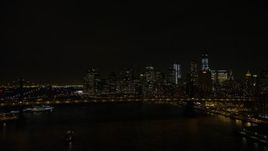4.8K aerial stock footage view fly over Manhattan Bridge to approach Brooklyn Bridge and Lower Manhattan skyline at night, New York Aerial Stock Footage | AX67_0080
