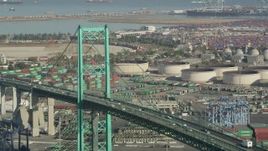 4.8K aerial stock footage of passing traffic on Vincent Thomas Bridge by cargo containers at the Port of Los Angeles, California Aerial Stock Footage | AX68_154