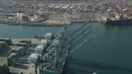 4.8K aerial stock footage fly over cargo cranes and pan to a ship docked at the Port of Los Angeles, California Aerial Stock Footage | AX68_166