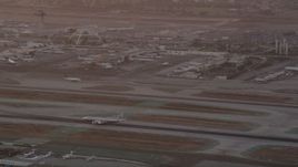 4.8K aerial stock footage track airliner on runway and tilt to reveal control tower and terminals at LAX at twilight, Los Angeles, California Aerial Stock Footage | AX69_012