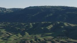 4K aerial stock footage Flyby green hills beside mountains in springtime, Gilroy, California Aerial Stock Footage | AX70_102