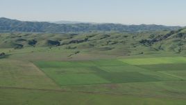 4K aerial stock footage Flyby farm fields beside green hills in Hollister, California Aerial Stock Footage | AX70_109