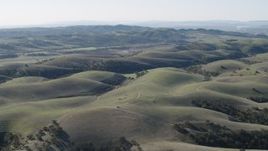 4K aerial stock footage Fly over dirt roads crossing hills to approach small farms in San Benito County, California Aerial Stock Footage | AX70_179