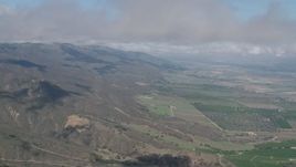 4K aerial stock footage of cloud-capped Santa Lucia Range mountain slopes and farmland in Soledad, California Aerial Stock Footage | AX70_264