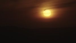4K aerial stock footage of the setting sun behind hazy clouds over mountains in Southern California Aerial Stock Footage | AX70_281