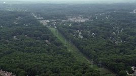 4.8K aerial stock footage of rows of power lines on a green strip between trees and suburbs in Burke, Virginia Aerial Stock Footage | AX74_135