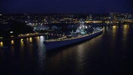 4.8K aerial stock footage approaching USS New Jersey battleship on the Delaware River, Camden, New Jersey, Night Aerial Stock Footage | AX81_001