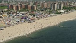 4.8K aerial stock footage flying by Luna Park, Riegelmann Boardwalk, and Coney Island Beach sunbathers, Brooklyn, New York City Aerial Stock Footage | AX83_220E
