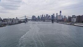 4K aerial stock footage tilt from ferry on the East River, and approach Manhattan and Brooklyn Bridge, Lower Manhattan skyline, New York City Aerial Stock Footage | AX84_101E