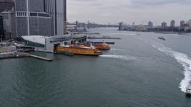 4K aerial stock footage tilt from the river to reveal ferries at the terminal and East River, Lower Manhattan, New York City Aerial Stock Footage | AX84_113
