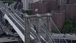 4K aerial stock footage of circling the American flag atop the Brooklyn Bridge, New York City Aerial Stock Footage | AX86_025