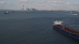 4K aerial stock footage tilt from water to reveal oil tanker sailing New York Harbor and Lower Manhattan skyline, New York, New York Aerial Stock Footage | AX88_089