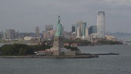 4K aerial stock footage of the Statue of Liberty on Liberty Island, Jersey City in the background, New York Aerial Stock Footage | AX88_194