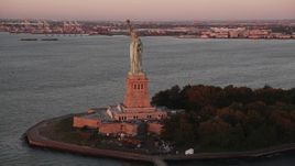 4K aerial stock footage Flying by Statue of Liberty, Liberty Island, New York, New York, sunrise Aerial Stock Footage | AX90_014