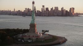 4K aerial stock footage of the Statue of Liberty, Lower Manhattan, revealing Brooklyn, New York, sunrise Aerial Stock Footage | AX90_017