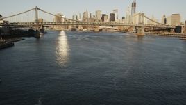 4K aerial stock footage of the East River, reveal Manhattan Bridge, Lower Manhattan, New York, sunrise Aerial Stock Footage | AX90_099