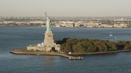 4K aerial stock footage Flying by the Statue of Liberty, New York Harbor, New York, New York, sunrise Aerial Stock Footage | AX90_138