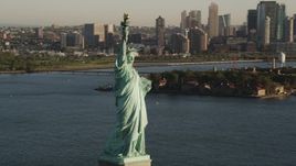 4K aerial stock footage of Statue of Liberty, Liberty Island, reveal Midtown Manhattan, New York, sunrise Aerial Stock Footage | AX90_142