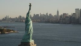 4K aerial stock footage of Statue of Liberty, revealing Freedom Tower, Lower Manhattan, New York, sunrise Aerial Stock Footage | AX90_143