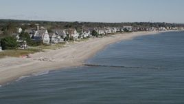 4K aerial stock footage of flying by a row of homes lining a beach in Fairfield, Connecticut Aerial Stock Footage | AX91_112