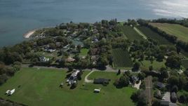 4K aerial stock footage of approaching waterfront homes and vineyard in Southold, New York Aerial Stock Footage | AX91_197