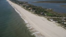 4K aerial stock footage of flying past a beach, tilt to reveal beachfront mansions, Southampton, New York Aerial Stock Footage | AX91_217