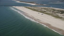 4K aerial stock footage tilt from water, revealing RVs on a beach and Shinnecock Inlet, Southampton, New York Aerial Stock Footage | AX91_229