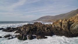 5K aerial stock footage of flying low over waves rolling toward coastal cliffs, Harmony, California Aerial Stock Footage | AXSF03_020