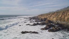 5K aerial stock footage of flying over hills, pan revealing coastal cliffs and ocean waves, Cambria, California Aerial Stock Footage | AXSF03_024
