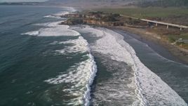 5K aerial stock footage pan from a small bridge and fly over ocean waves in San Simeon, California Aerial Stock Footage | AXSF03_035