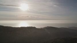 5K aerial stock footage of the sun high above the ocean, seen from the hills, Big Sur, California Aerial Stock Footage | AXSF03_106