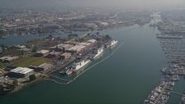5K aerial stock footage pass ships docked at Coast Guard Island, approach warehouses and factories by the Oakland Estuary, California Aerial Stock Footage | AXSF05_087