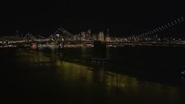 5K aerial stock footage flying away from the Bay Bridge, skyline in the background, San Francisco, California, night Aerial Stock Footage | AXSF07_085