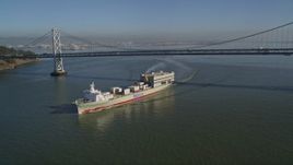 5K aerial stock footage track a cargo ship sailing away from the Bay Bridge, San Francisco, California Aerial Stock Footage | AXSF09_061