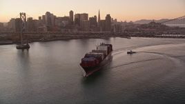 5K aerial stock footage of a cargo ship sailing under Bay Bridge, reveal Downtown San Francisco skyline, California, sunset Aerial Stock Footage | AXSF10_065