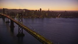 5K aerial stock footage of a reverse view of the Bay Bridge and skyline of Downtown San Francisco, California, twilight Aerial Stock Footage | AXSF10_104
