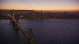 5K aerial stock footage reverse view of heavy Bay Bridge traffic and Downtown San Francisco, California, twilight Aerial Stock Footage | AXSF10_105