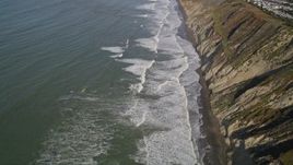 5K aerial stock footage of flying away from ocean waves rolling toward coastal cliffs, Daly City, California Aerial Stock Footage | AXSF15_035
