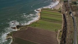 5K aerial stock footage of a reverse view of crop fields by Highway 1, train tracks, Davenport, California Aerial Stock Footage | AXSF15_085