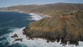 5K aerial stock footage of a reverse view of the Point Sur Light Station, waves crashing against coastline, Big Sur, California Aerial Stock Footage | AXSF16_089