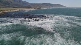 5K aerial stock footage tilt from ocean, reveal seagulls flying over rocks along coast, Big Sur, California Aerial Stock Footage | AXSF16_091