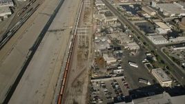 HD stock footage aerial video reverse view of train between river and warehouses, Vernon, California Aerial Stock Footage | CAP_004_027