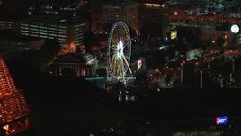 HD stock footage aerial video of flying by the top of a skyscraper to reveal a Ferris wheel at nighttime, Downtown Atlanta, Georgia Aerial Stock Footage | CAP_013_062